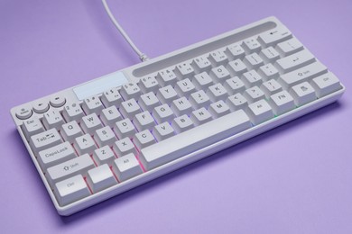 Photo of White keyboard with RGB lighting on violet background, closeup