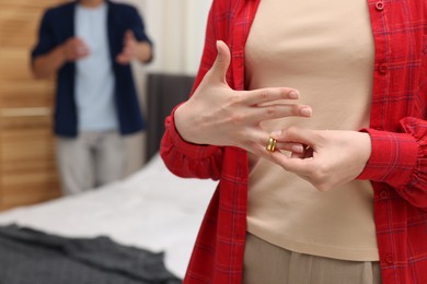 Photo of Woman taking off engagement ring after her husband's betrayal indoors, selective focus
