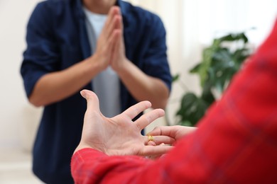 Photo of Woman taking off engagement ring after her husband's betrayal indoors, selective focus