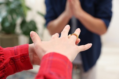 Photo of Woman taking off engagement ring after her husband's betrayal indoors, selective focus