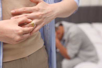 Photo of Woman taking off engagement ring after her husband's betrayal indoors, selective focus