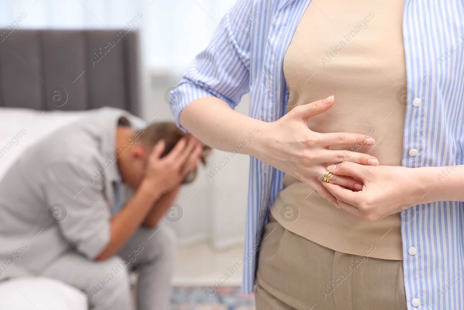 Woman taking off engagement ring after her husband's betrayal indoors, selective focus Photo of Woman taking off engagement ring after her husband's betrayal indoors, selective focus