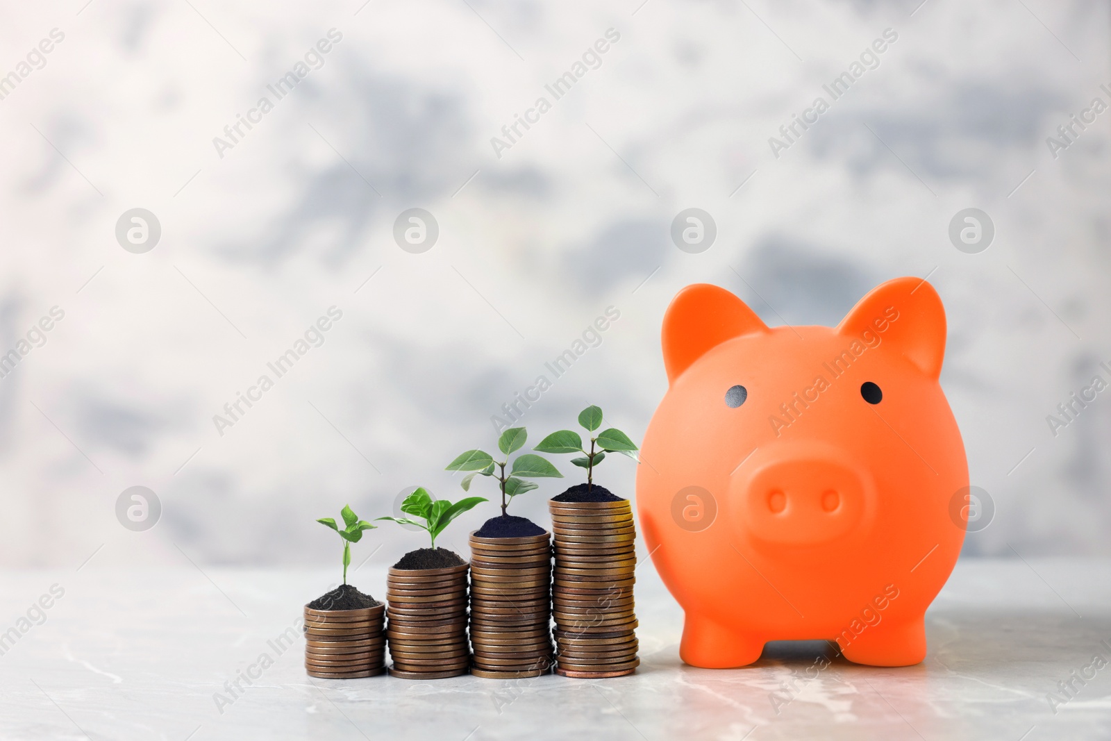 Image of Savings concept. Stacked coins with sprouts on tops and piggy bank on table