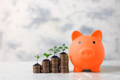 Image of Savings concept. Stacked coins with sprouts on tops and piggy bank on table