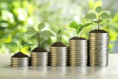 Image of Savings concept. Stacked coins with sprouts on table