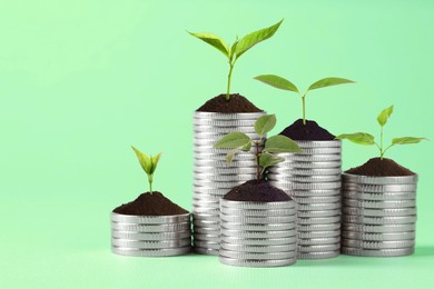 Image of Savings concept. Stacked coins with sprouts on aquamarine background