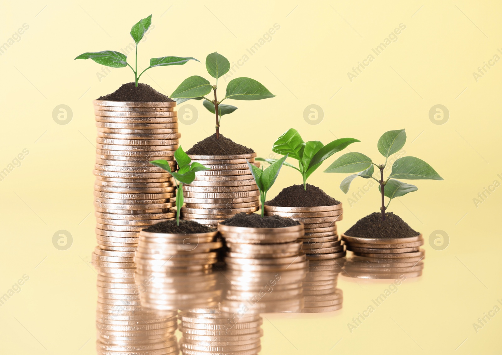 Image of Savings concept. Stacked coins with sprouts on beige background