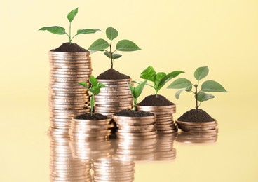 Image of Savings concept. Stacked coins with sprouts on beige background
