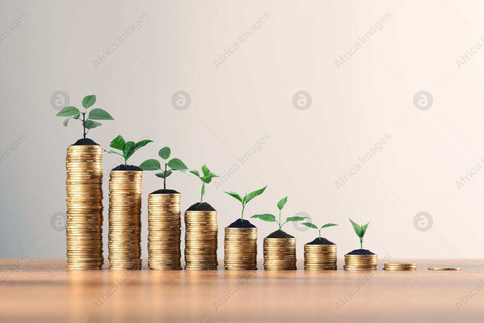 Image of Savings concept. Stacked coins with sprouts on wooden table