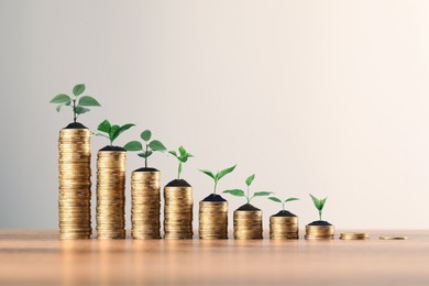Image of Savings concept. Stacked coins with sprouts on wooden table