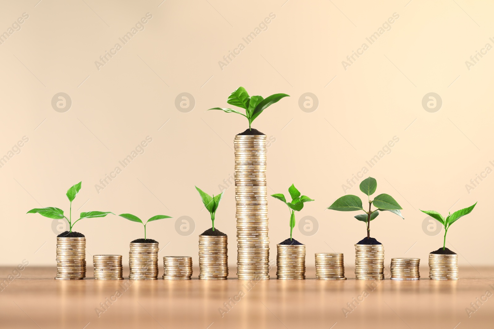 Image of Savings concept. Stacked coins with sprouts on wooden table