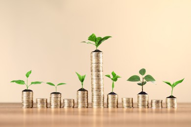 Image of Savings concept. Stacked coins with sprouts on wooden table