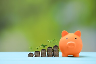 Image of Savings concept. Stacked coins with sprouts on tops and piggy bank on table