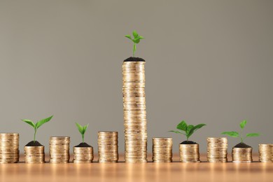 Image of Savings concept. Stacked coins with sprouts on wooden table