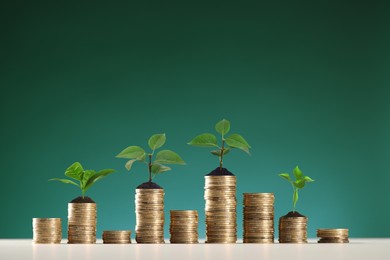 Image of Savings concept. Stacked coins with sprouts on table against green background