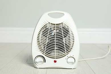 Photo of Modern electric fan heater on floor in room