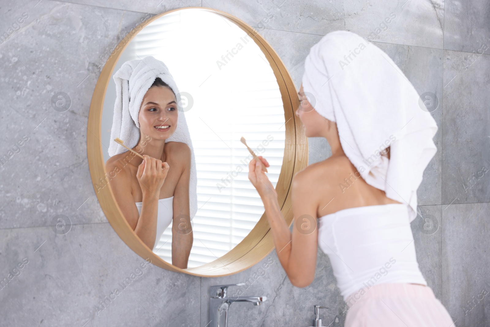 Photo of Getting ready. Young woman brushing her teeth near mirror at home