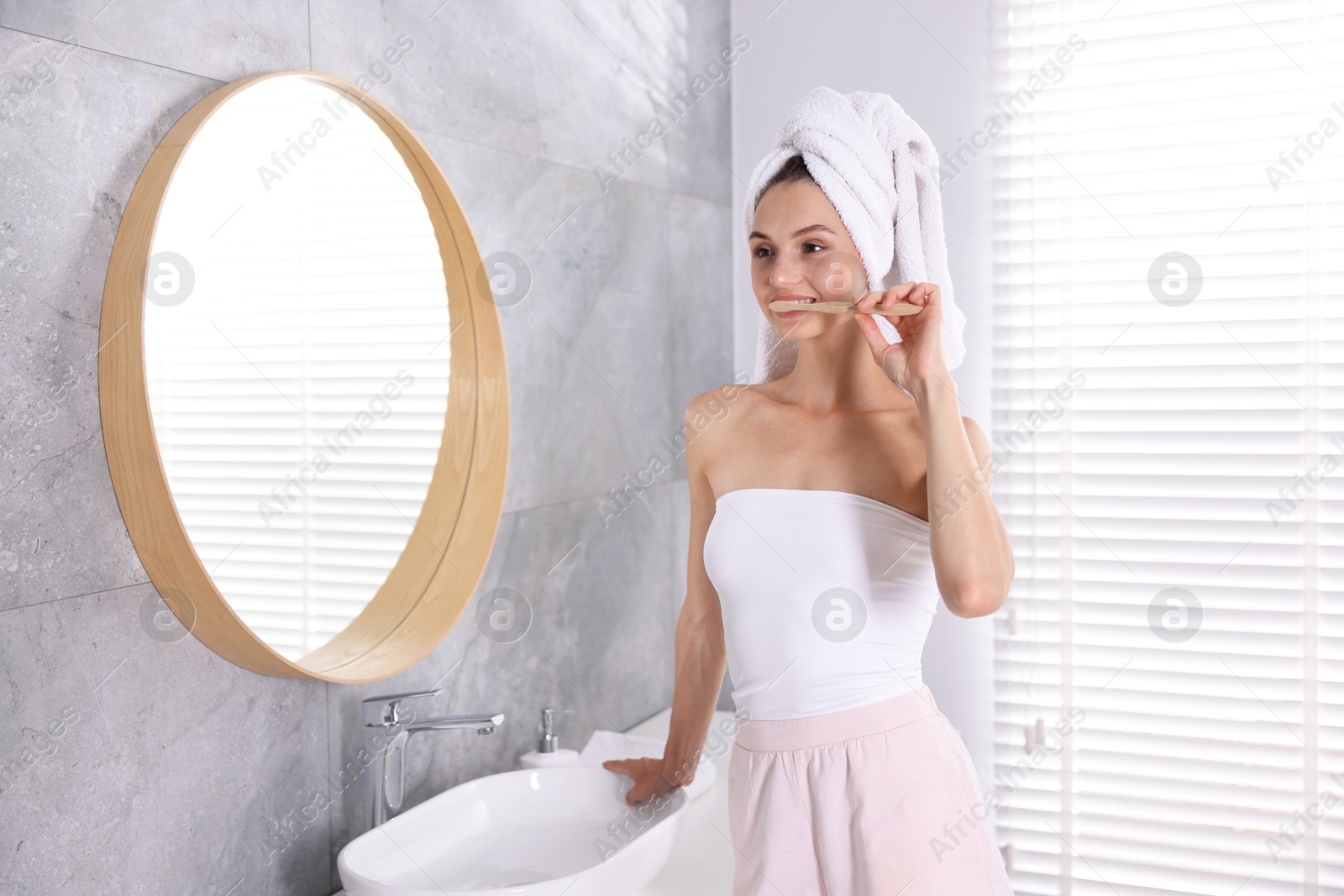 Photo of Getting ready. Young woman brushing her teeth near mirror at home