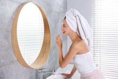 Photo of Getting ready. Young woman brushing her teeth near mirror at home