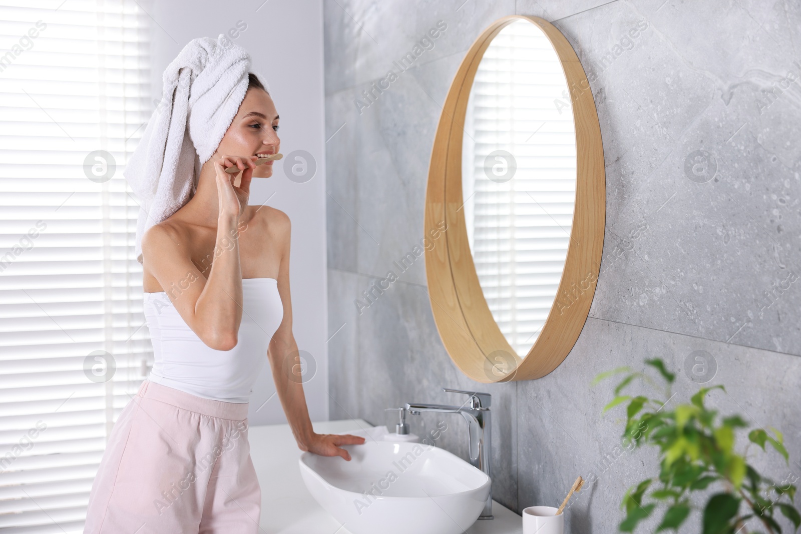 Photo of Getting ready. Young woman brushing her teeth near mirror at home