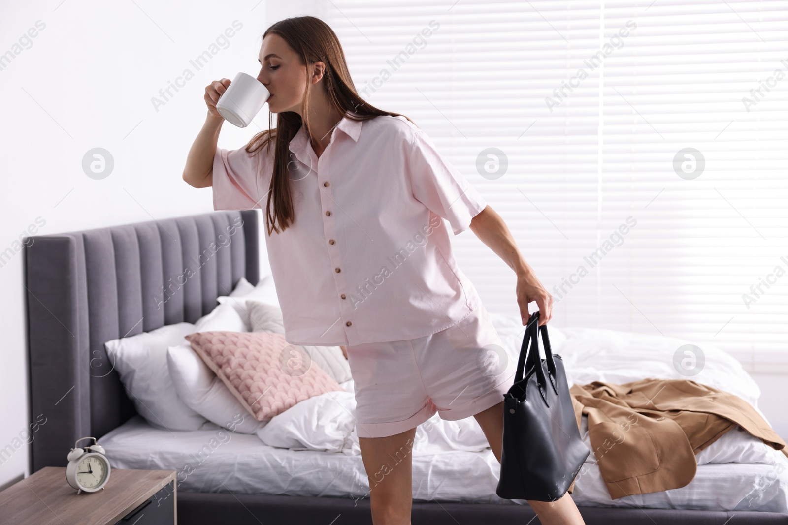 Young woman with cup of coffee getting ready at home Photo of Young woman with cup of coffee getting ready at home