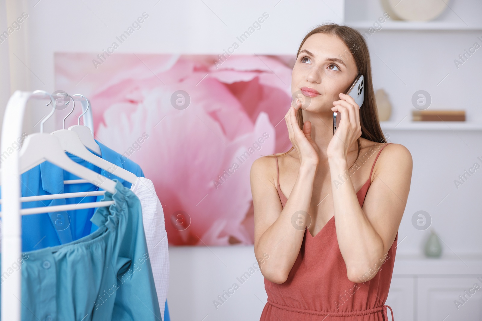 Getting ready. Young woman talking on phone and choosing clothes at home Photo of Getting ready. Young woman talking on phone and choosing clothes at home
