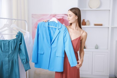 Photo of Getting ready. Young woman choosing clothes at home