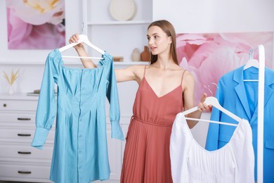 Photo of Getting ready. Young woman choosing clothes at home