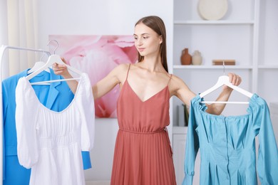 Photo of Getting ready. Young woman choosing clothes at home