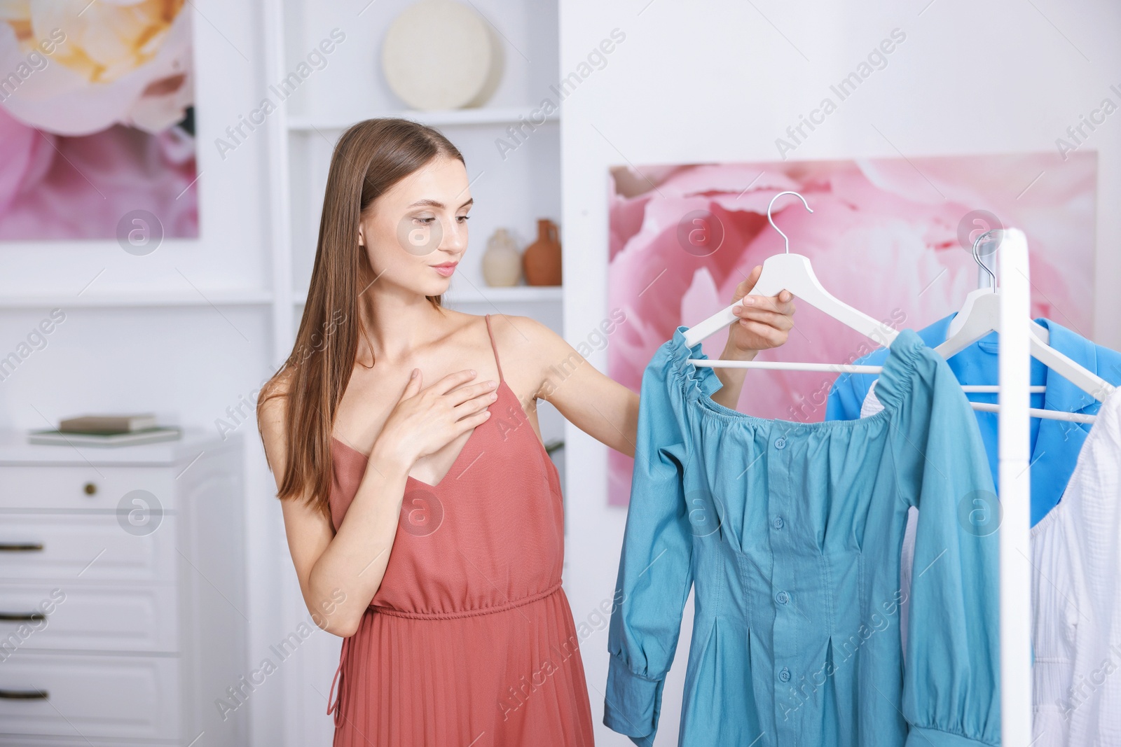 Photo of Getting ready. Young woman choosing clothes at home
