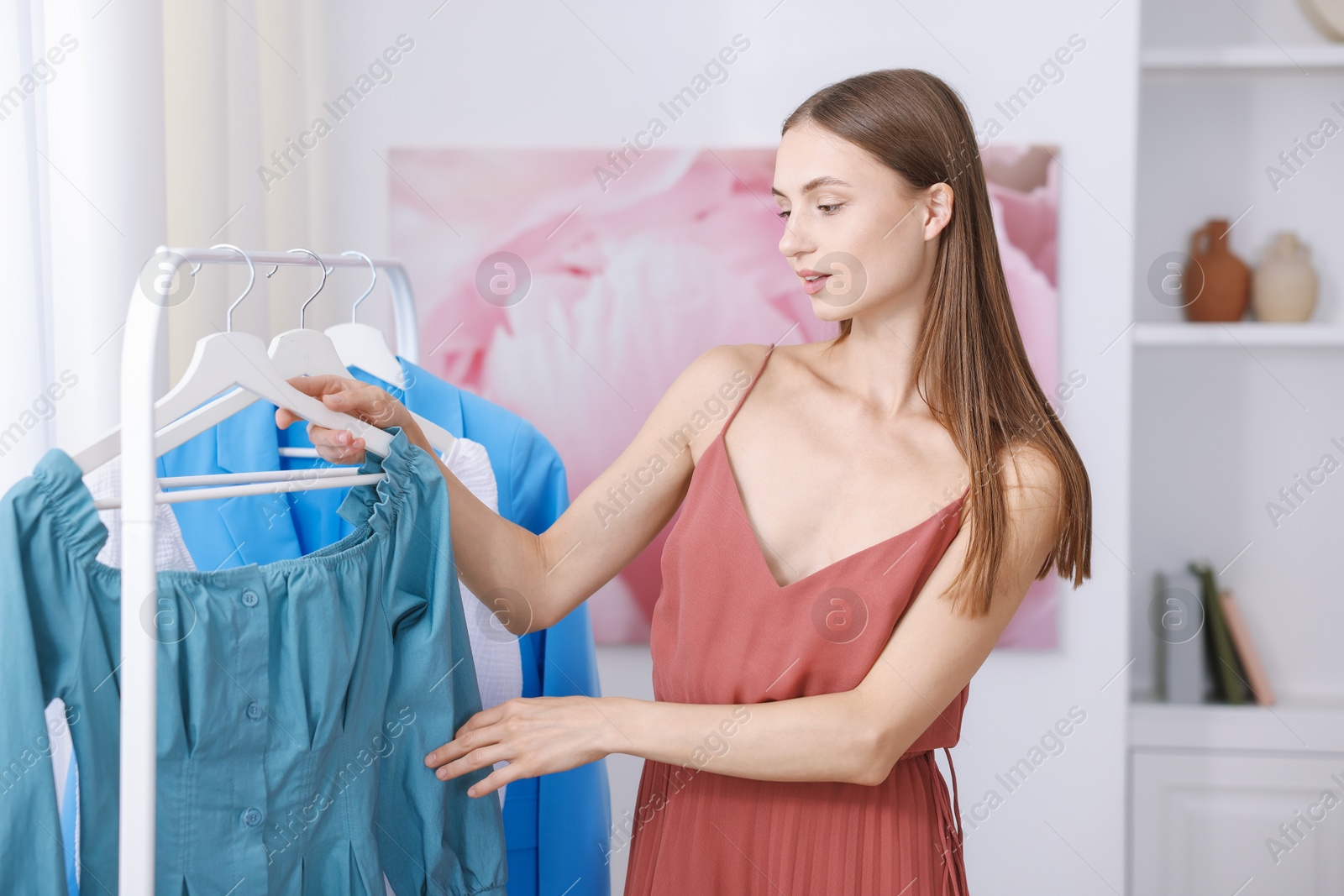 Photo of Getting ready. Young woman choosing clothes at home