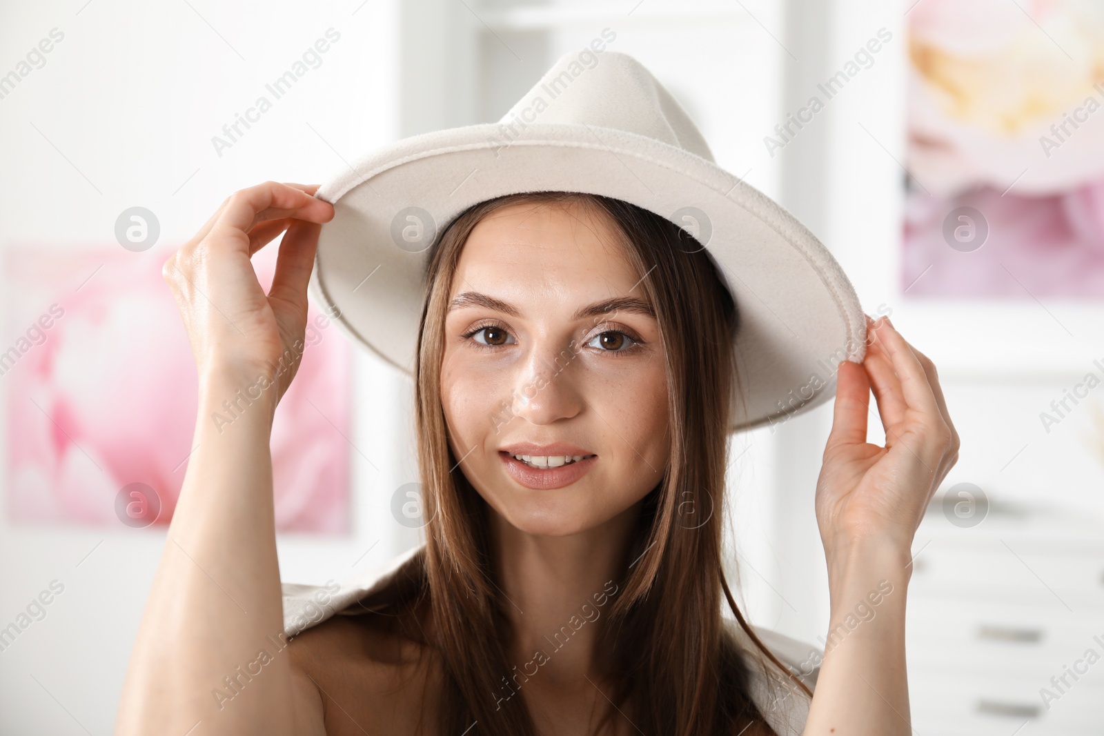 Photo of Getting ready. Young woman in stylish hat at home