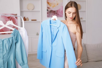 Photo of Getting ready. Young woman choosing clothes at home