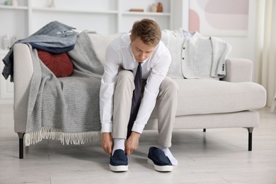 Photo of Getting ready. Young man putting on stylish shoes at home