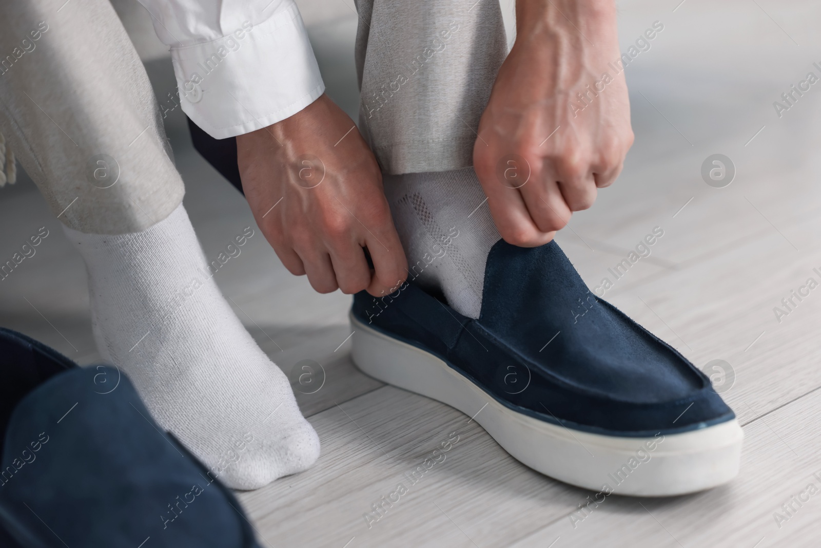 Photo of Getting ready. Young man putting on stylish shoes at home, closeup