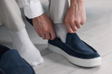 Photo of Getting ready. Young man putting on stylish shoes at home, closeup