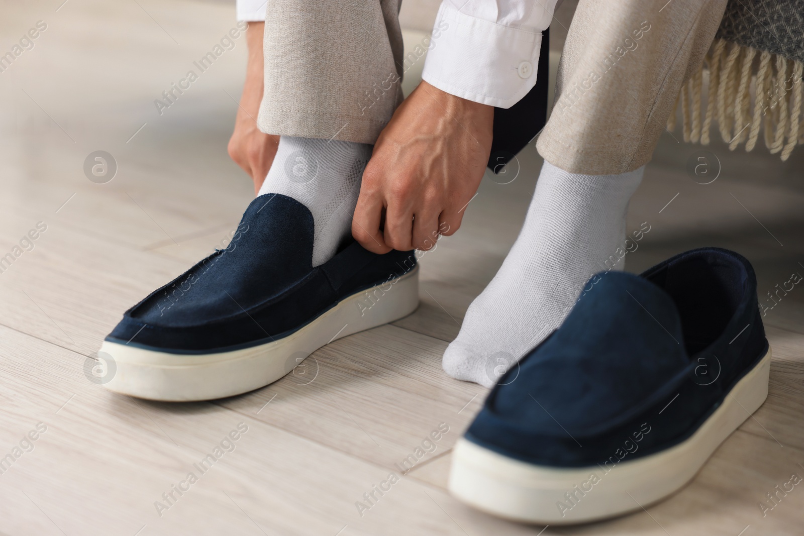 Photo of Getting ready. Young man putting on stylish shoes at home, closeup