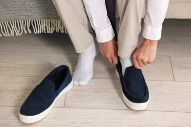 Photo of Getting ready. Young man putting on stylish shoes at home, closeup