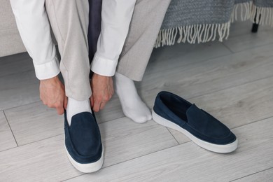 Photo of Getting ready. Young man putting on stylish shoes at home, closeup