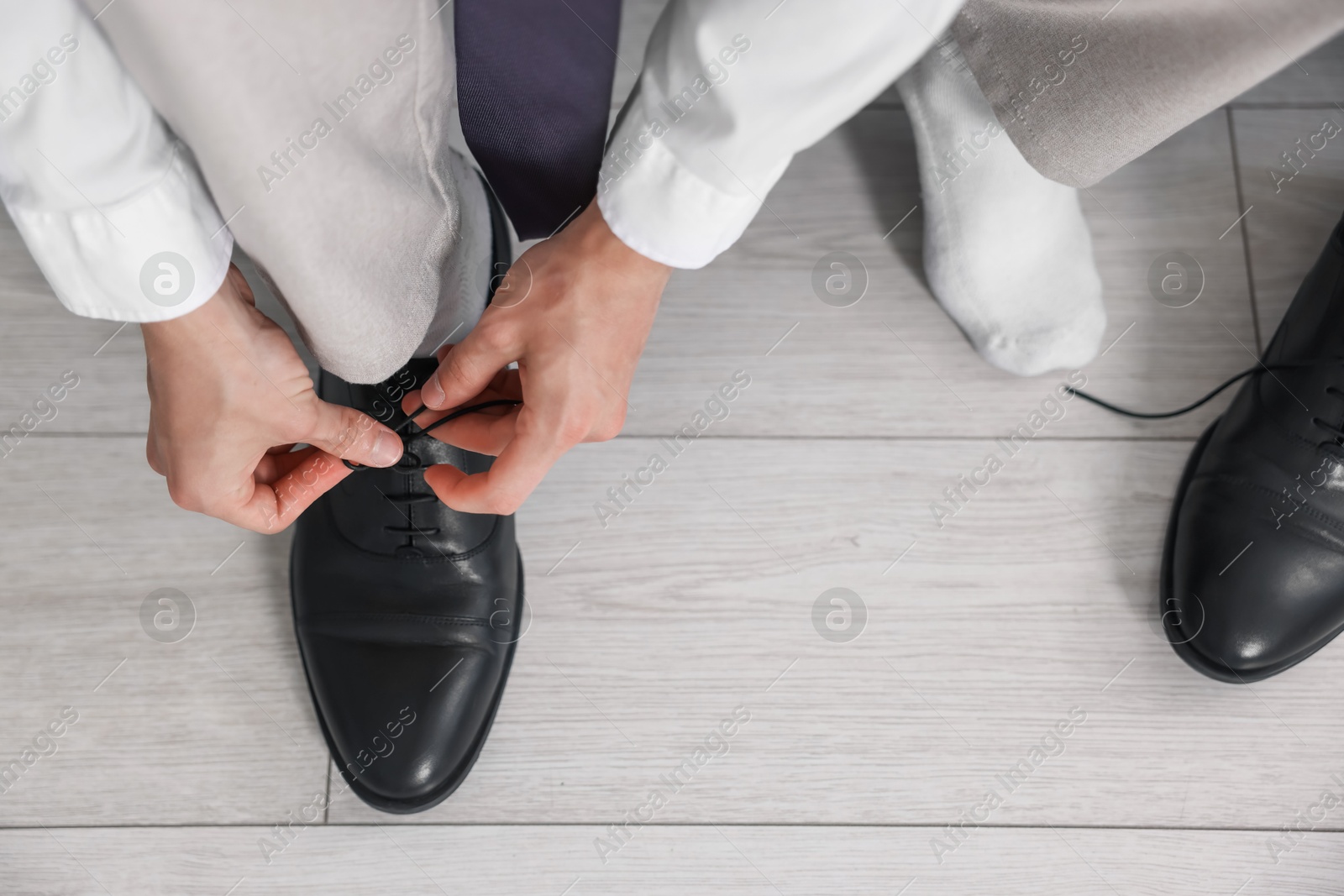 Photo of Getting ready. Young man putting on stylish shoes at home, closeup