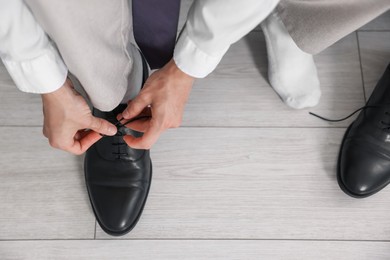 Photo of Getting ready. Young man putting on stylish shoes at home, closeup