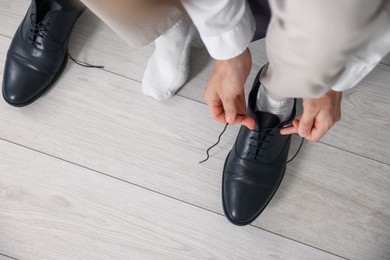 Photo of Getting ready. Young man putting on stylish shoes at home, closeup