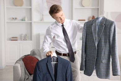 Photo of Getting ready. Young man choosing clothes at home
