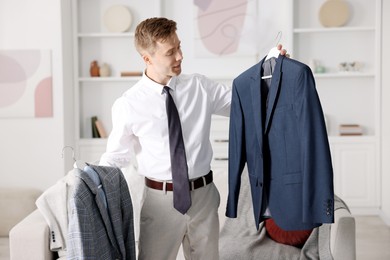 Photo of Getting ready. Young man choosing clothes at home