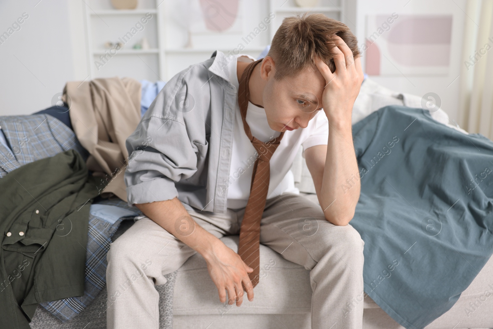 Photo of Getting ready. Stressed young man choosing clothes at home