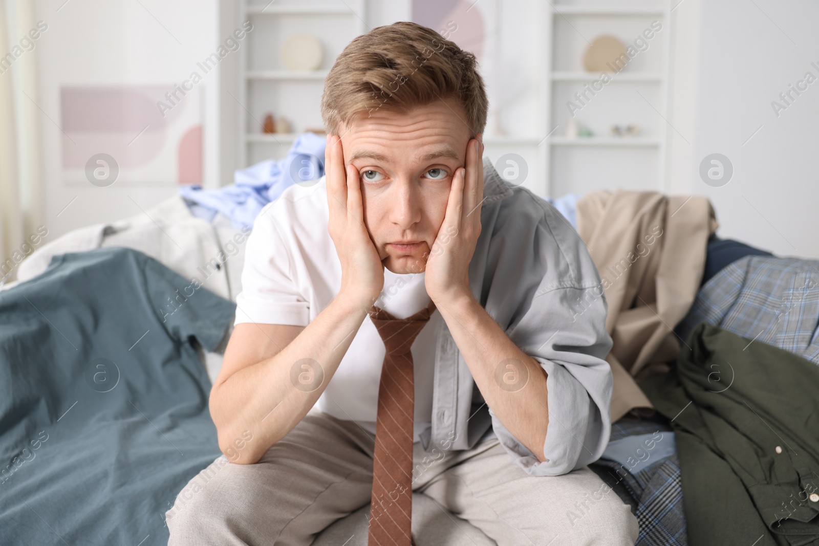 Photo of Getting ready. Stressed young man choosing clothes at home