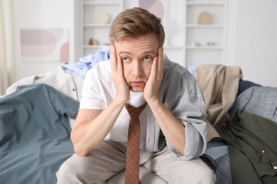 Photo of Getting ready. Stressed young man choosing clothes at home