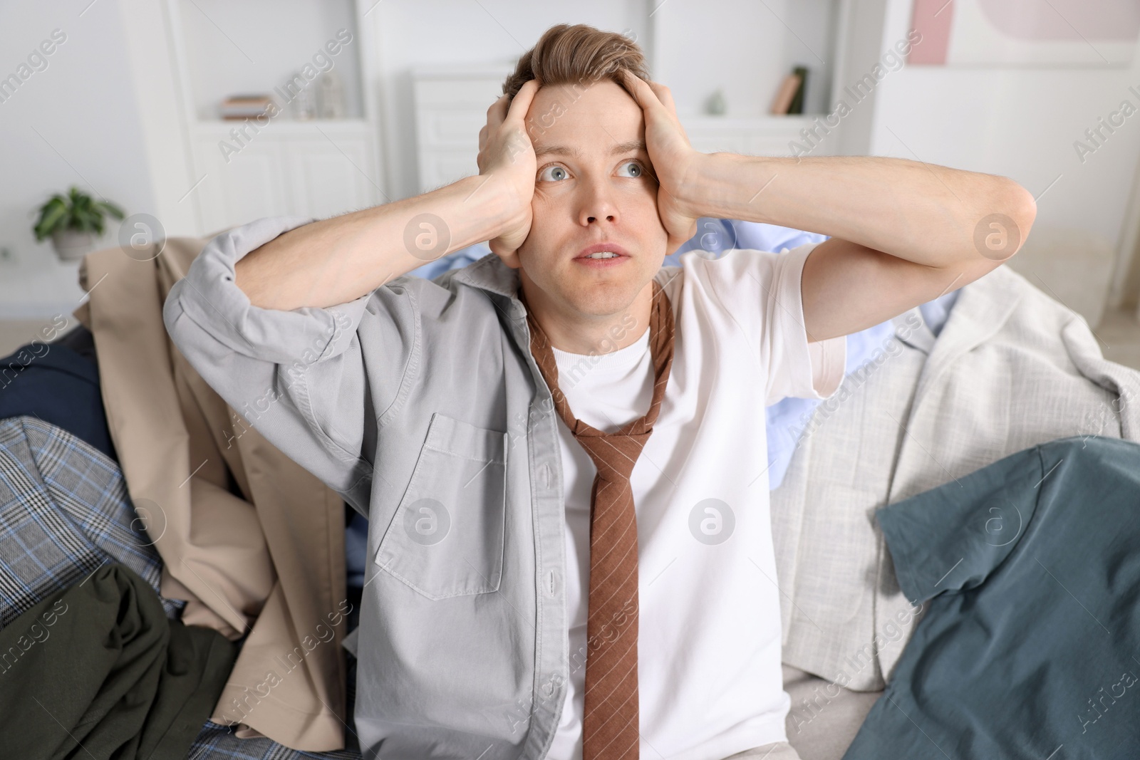 Photo of Getting ready. Stressed young man choosing clothes at home