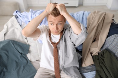 Photo of Getting ready. Stressed young man choosing clothes at home