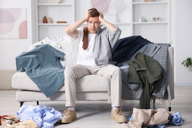 Photo of Getting ready. Stressed young man choosing clothes at home